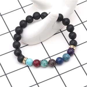 Lava rock chakra bead bracelet with seven colored stones on white ceramic hand display