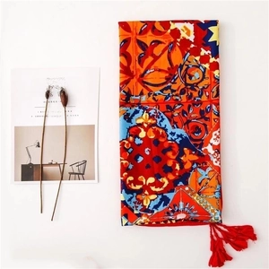 Detail of bohemian print shawl with colorful floral patterns and red tassels decoration