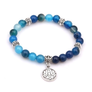Détail du bracelet en perles de pierre bleue avec pendentif lotus argenté et symbole Om