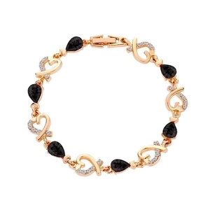 Detailed close-up of golden heart bracelet with black teardrop crystals and white zircon