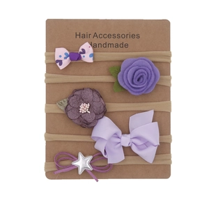 Detail of five handmade infant headbands with fabric flowers and bows on nude elastic straps