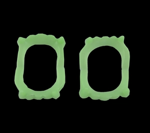 Macro detail of two-pack neon green fluorescent vampire plastic fangs for Halloween props