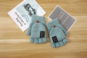 Detail of blue-grey knitted flip top gloves with wooden button and fashion label