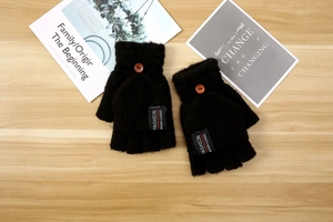 Detail of black knitted flip top gloves with wooden button and fashion woven label