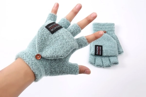 Detail of light blue knitted flip top mittens with wooden button and fashion label