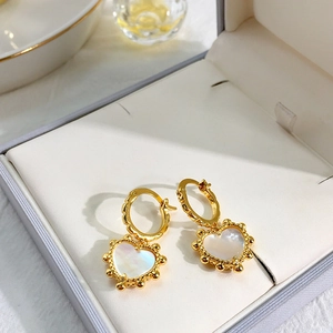 Macro detail of heart-shaped clover earrings in gold with iridescent shell inlay