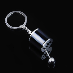 Detailed view of silver car gear shifter keychain on a reflective black surface