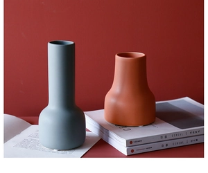 Primer plano de jarrones de cerámica mate sobre revistas con diseño nórdico elegante