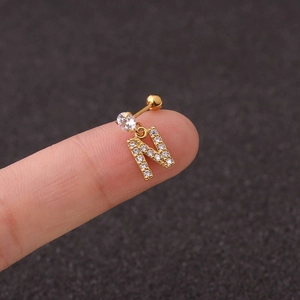 Close-up of golden letter N stud earring with zircon stones held on finger tip