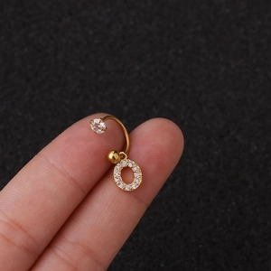 Gros plan d'une boucle d'oreille en acier doré avec un pendentif lettre O en zircone