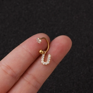 Vue macro d'un piercing d'oreille en U doré avec pendentif lettre serti de zircons