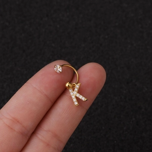 Gros plan d'un piercing de nombril doré avec pendentif lettre K et zircons brillants
