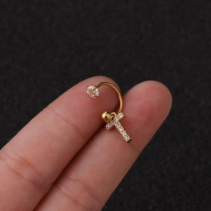 Gros plan d'une boucle d'oreille lettre C dorée avec zircone tenue entre les doigts