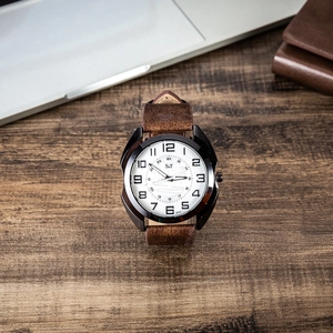 Close-up of leather strap watch with dual 12/24-hour display on a wooden desk setup