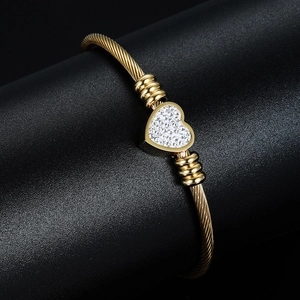 Close-up of golden cable texture cuff bracelet featuring a sparkling rhinestone heart charm
