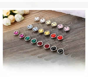 Macro view of 14-color square zircon earrings in stainless steel on wooden surface