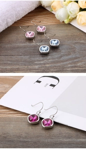 Detail view of square cut zircon earrings in pink, light blue, and magenta gemstone colors