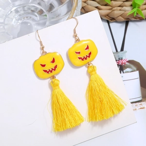 Detail of yellow pumpkin face earrings with long tassels on a white display card