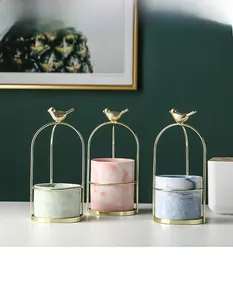 Detail of three marble texture ceramic pots in golden metal frames with bird decor