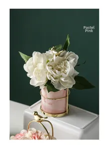Detail of pink marble vase with gold metal bird stand holding white flowers