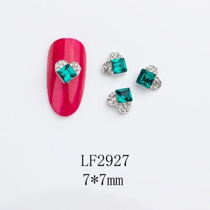Detail of 7x7mm heart-shaped silver frame nail charms with emerald green square stones
