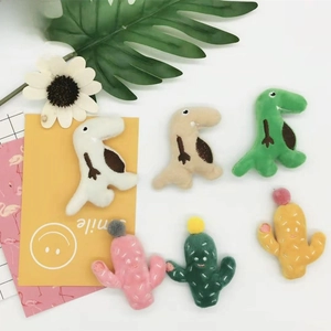 Detail view of colorful plush dinosaur and cactus patches for bags and accessories
