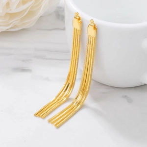 Close-up of golden multi-layer long chain tassel earrings with glossy metal finish