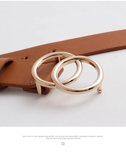 Close-up of brown leather belt with polished gold-tone double ring buckle detail