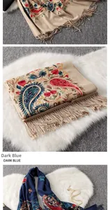 Close-up of heavy paisley embroidery and fringe detail on warm dark blue ethnic shawl