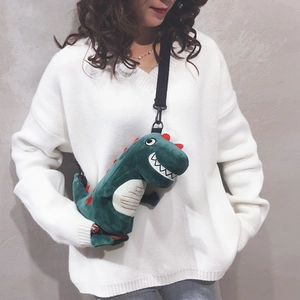 Cute green plush dinosaur crossbody bag with adjustable strap worn by model on white sweater