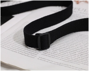 Detailed macro view of the black canvas shoulder strap with a plastic adjustment buckle