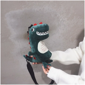 Detail view of a cute plush green dinosaur shoulder bag with adjustable black strap