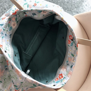 Detail view of floral tote bag with green lining, interior pocket, and secure zipper closure