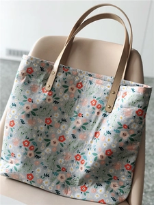 Detail of floral tote bag with daisy pattern and premium leather handles with metal rivets