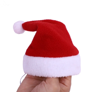 Close-up of small red and white Christmas pet hat with elastic strap held by hand