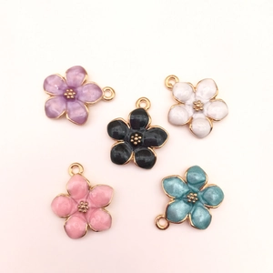 Detailed flat lay of colorful enamel cherry blossom pendants with gold metal frames for DIY