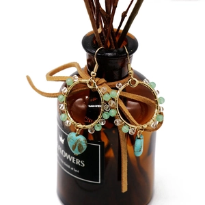Detail of bohemian gold hoop earrings with turquoise charms and light green beads