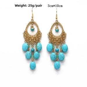 Detail of bohemian gold hollow teardrop earrings with turquoise textured beads