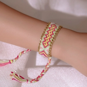 Detail of hand-woven friendship bracelet with pink yellow patterns and gold side chains