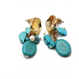 Detail of bohemian drop earrings with turquoise stones, gold metal texture and pearls