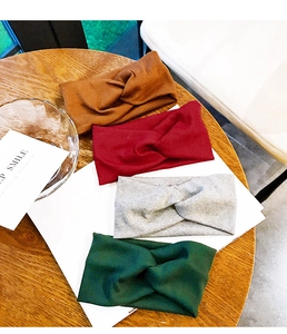 Knitted ribbed twist headbands in four colors displayed on a rustic wooden background