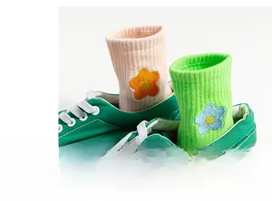 Detailed embroidery of flowers on pink and green cotton crew socks in canvas sneakers