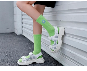 Detail of white platform sandals worn with green floral embroidered crew socks