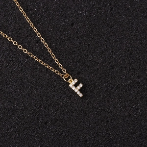 Macro detail of a golden letter F pendant necklace with sparkling zircon pavé setting