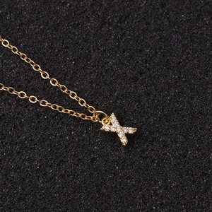 Macro view of gold-tone O-chain necklace with sparkling X-shaped zircon pendant