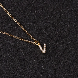 Detailed close-up of golden V letter pendant necklace with sparkling zircon stones