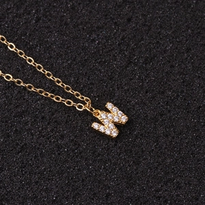 Macro detail of gold letter W pendant with sparkling cubic zirconia on fine O-chain