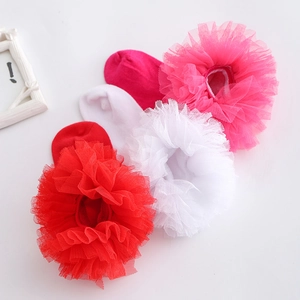 Detail von roten weißen und rosa Kindersocken mit großen Tüll Rüschen und Spitze
