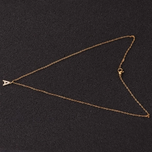Minimalist gold necklace with zircon letter A pendant on a textured black surface