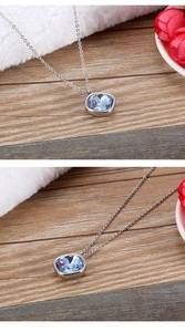 Detailed view of 15mm square blue crystal pendant with silver chain on a wood surface
